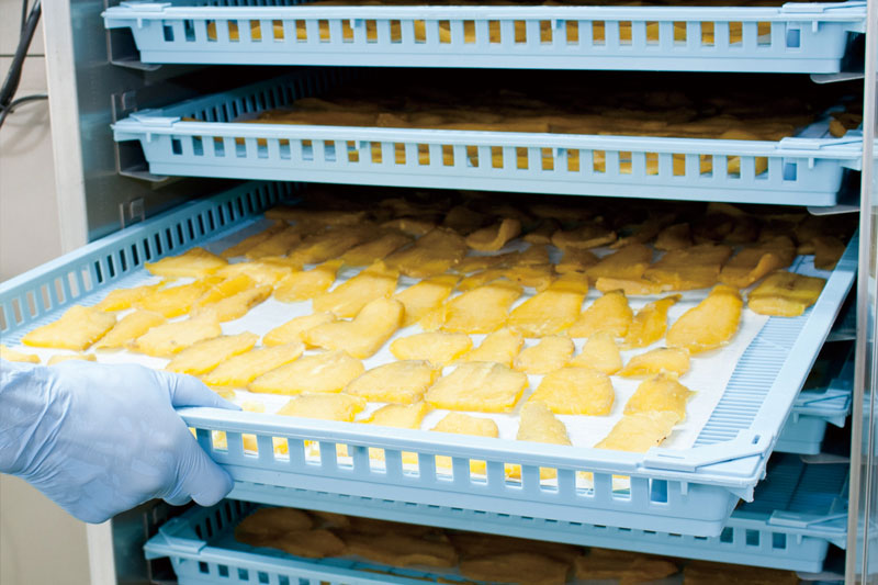 干し芋の製造工程写真-5。大崎町近隣で栽培されたさつま芋の紅はるかを㈱コーセンの本社工場でスライス加工した後に、やわらかくしっとり感を残した乾燥作業。丁寧に乾燥調整した干し芋はOEM製造。
